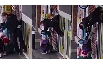 Il cappotto si incastra nella saracinesca di un negozio: 72enne viene sollevata e rimane appesa a testa in giù – VIDEO