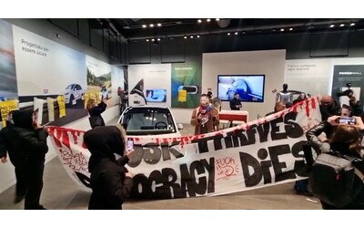 Blitz in una concessionaria Tesla di Milano, attivisti entrano con le maschere di Musk: “Lui prospera, la democrazia muore”